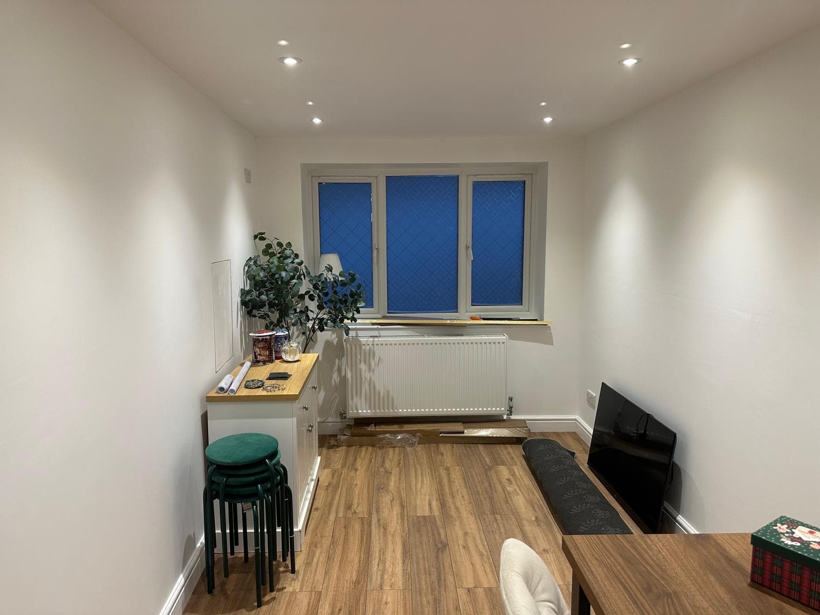 A converted garage finished as a dining room, with a new window, a radiator beneath it and wood-effect flooring