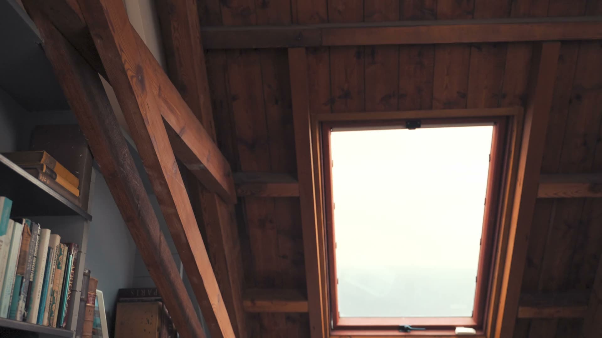 A loft conversion in use as a home office, with a rooflight and shelving built into the eaves