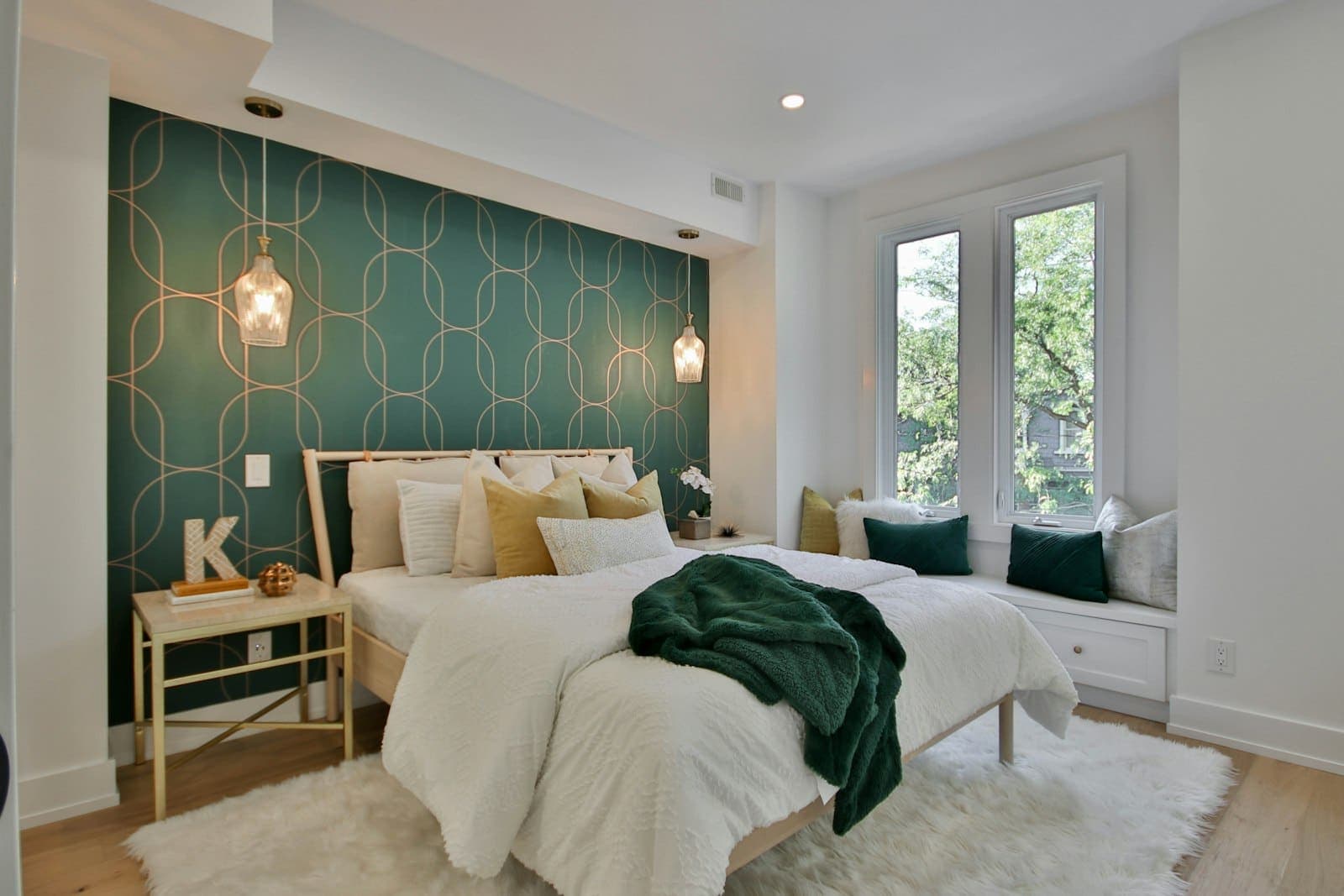 A bright double bedroom with a feature wall, bedside table and a window seat