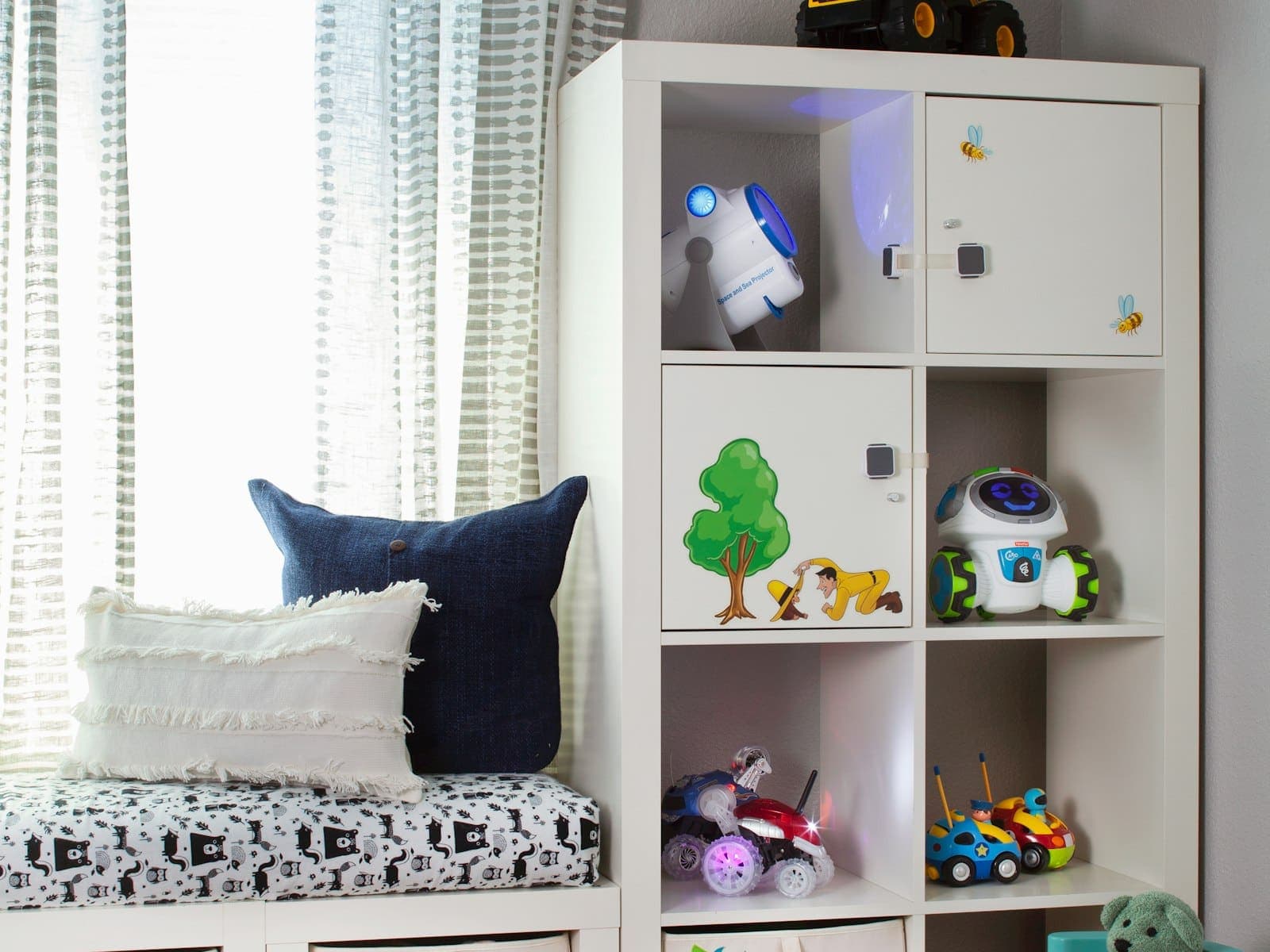 A playroom with cube storage full of toys and a cushioned window seat