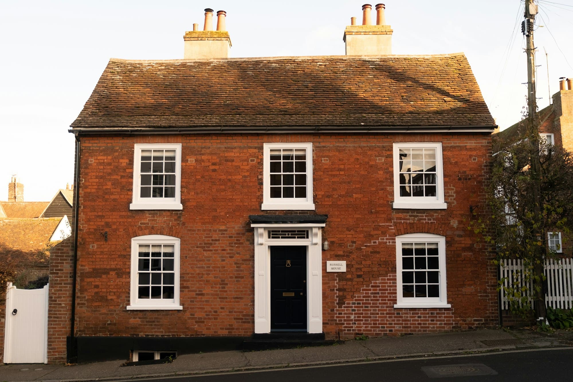 A red brick house with white sash windows and a black front door