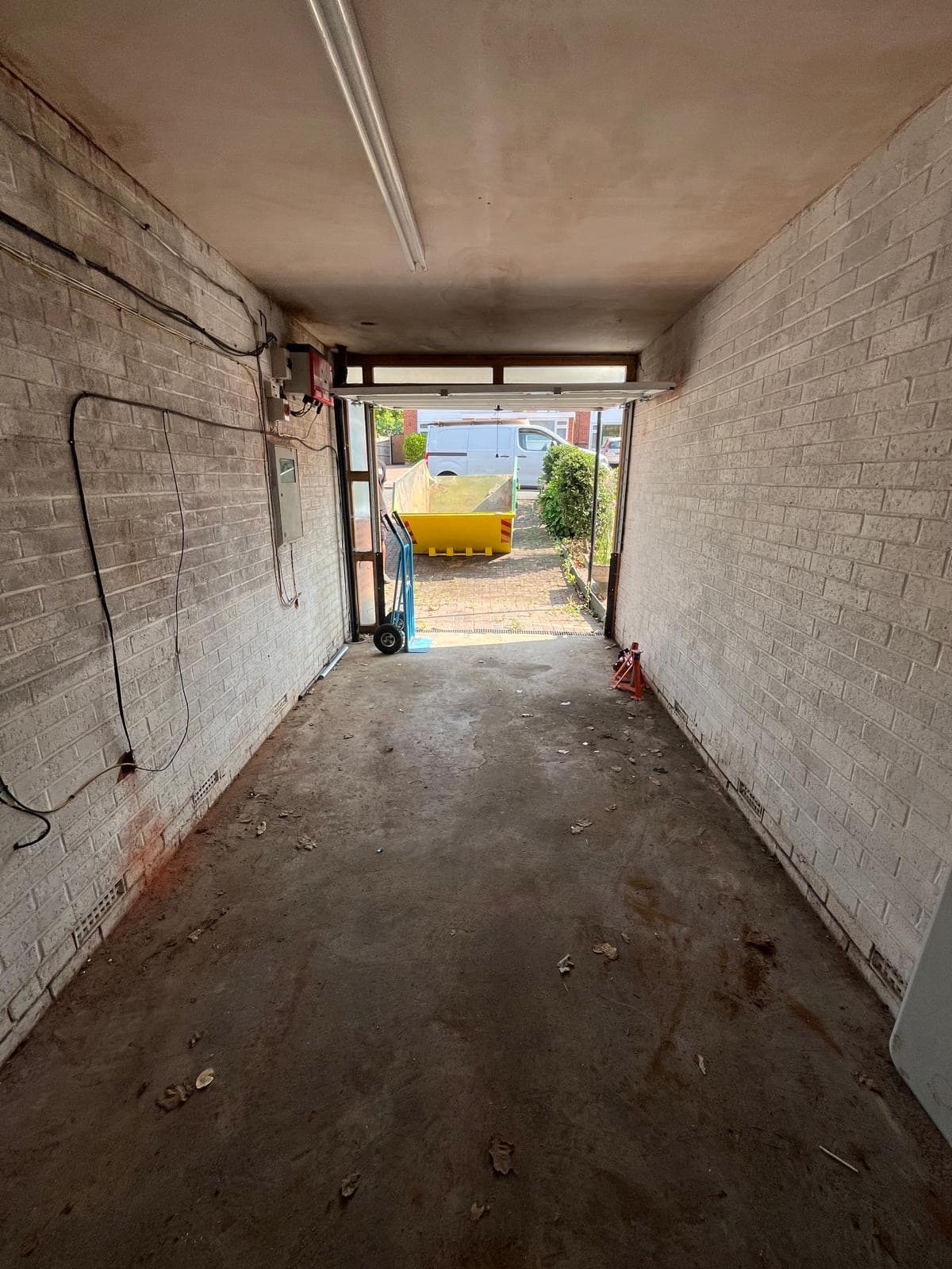 The inside of an emptied garage with painted block walls, a bare concrete floor and surface wiring