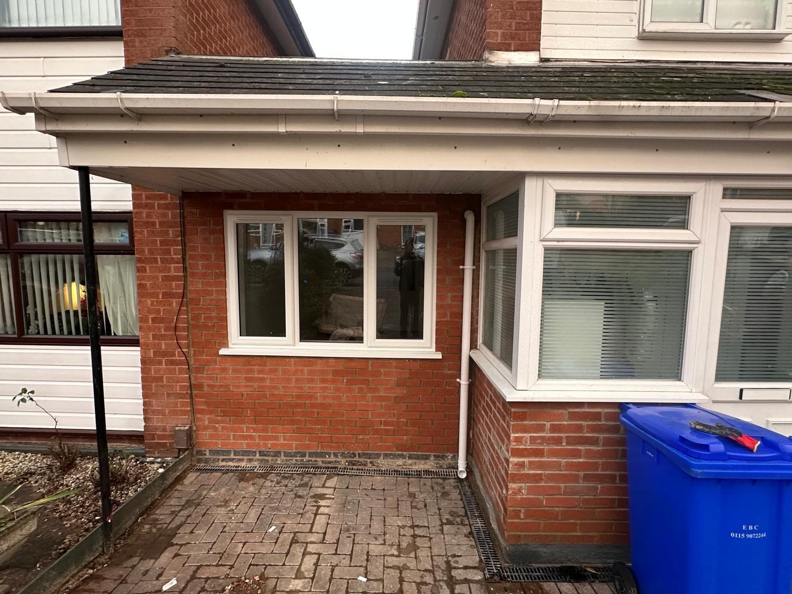 The finished brick infill wall and white window where the garage door used to be, with a new drainage channel below