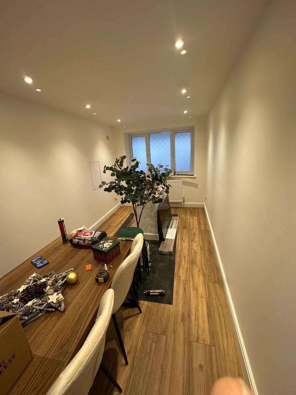 The finished room in use as a dining room, with a long table, chairs, wood-effect flooring and recessed lighting